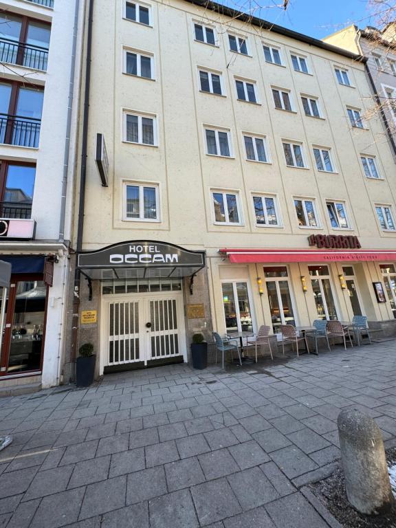 慕尼黑Hotel Occam的一座大建筑前面设有桌椅