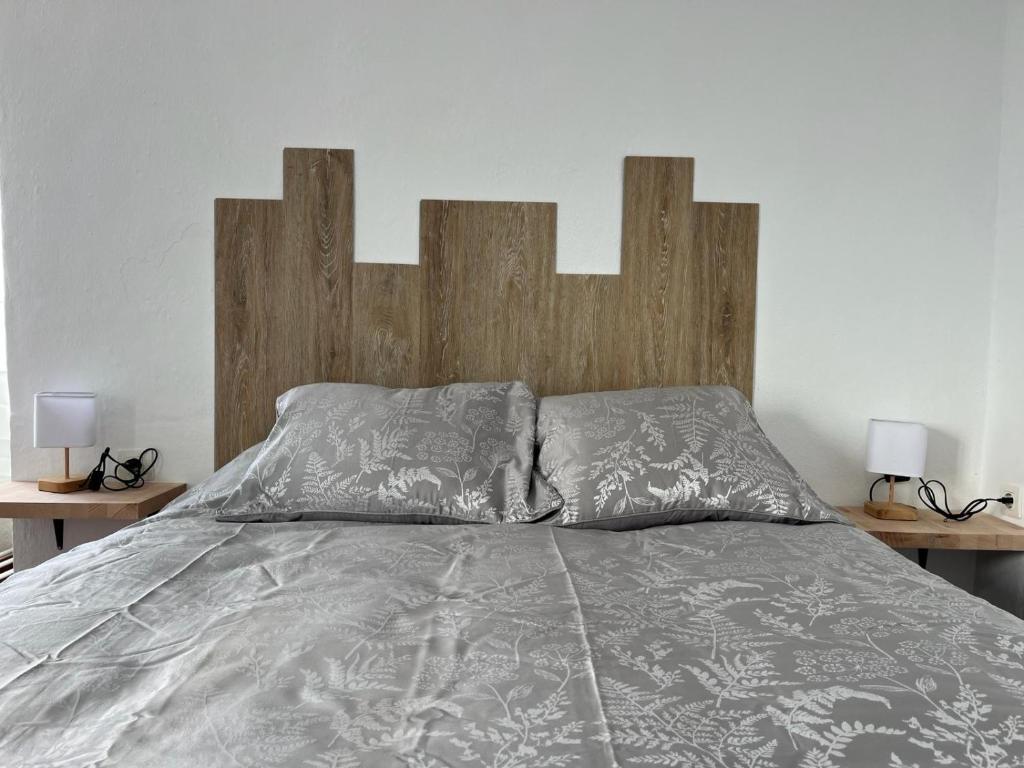 米哈斯ALMAFUERTE的一张带木头床头板和两盏灯的床