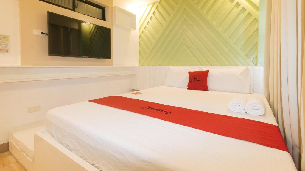 达沃市RedDoorz @ Innzz Apartel的卧室配有白色的床和红色枕头