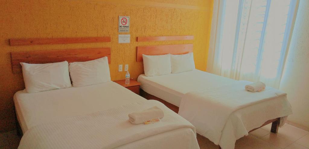 科米坦德多明格斯Hotel Central Comitán的酒店客房,配有两张带白色床单的床