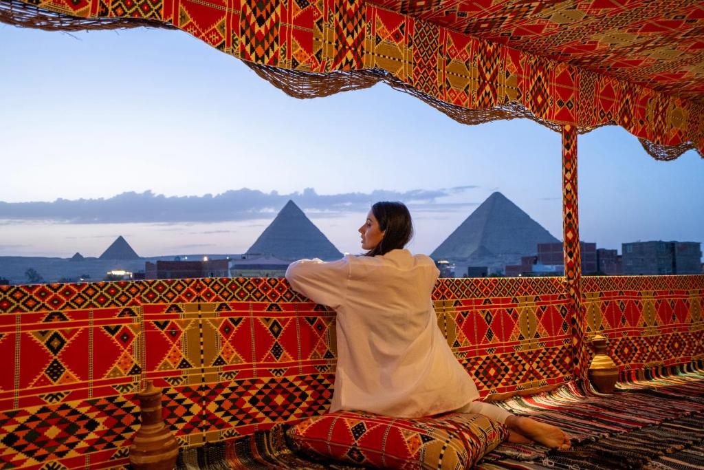 开罗king of pharaohs pyramids view的坐在有金字塔的长凳上的女人