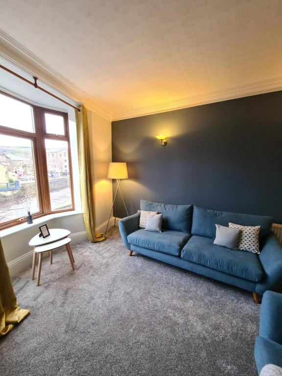 MytholmroydStunning River View的客厅设有蓝色的沙发和窗户。