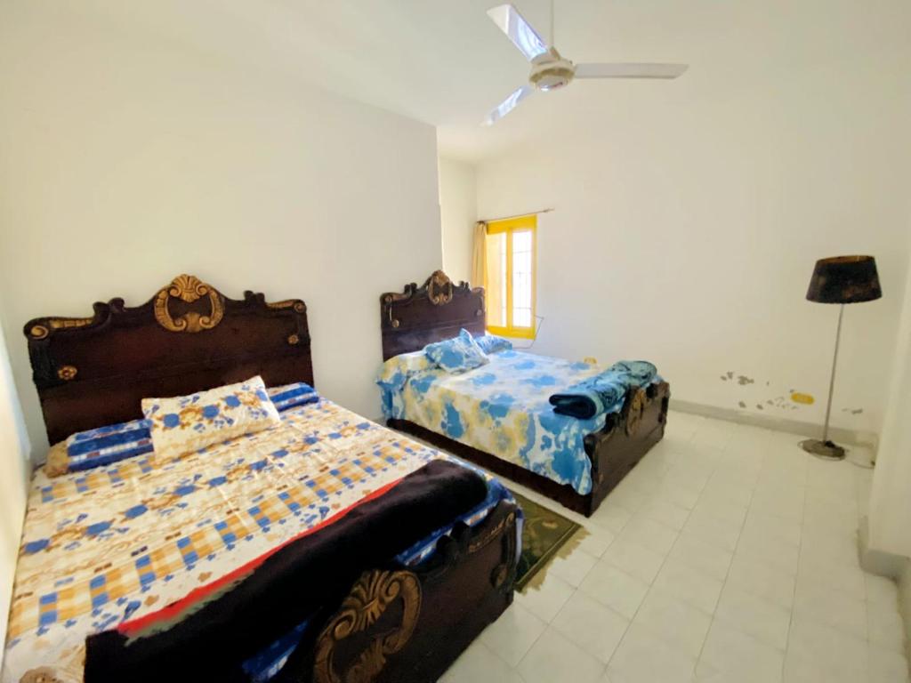 ‘Ezbet el-Ibrâshiفيلا in fayed的一间卧室配有两张床和吊扇