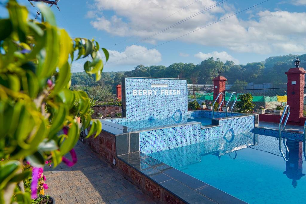 马哈巴莱斯赫瓦尔Berry Fresh Stays Mahabaleshwar With Pool的一个带阅读能源酒店标志的度假游泳池