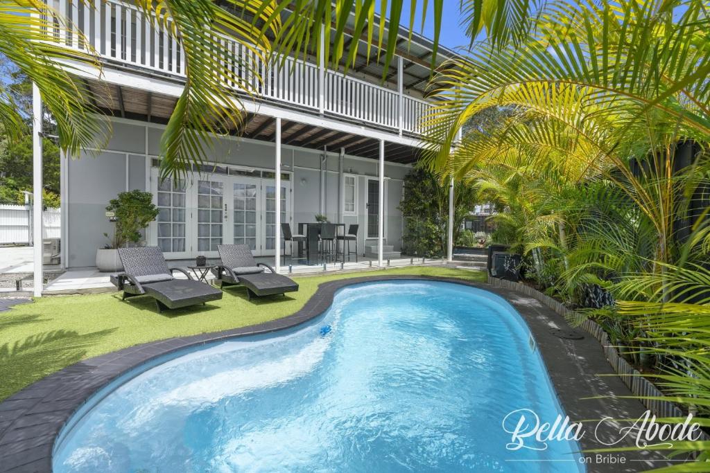 邦加里Bella Abode on Bribie - Loft with Pool的棕榈树房子后院的游泳池