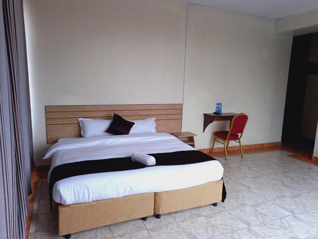内罗毕Fahari Bliss Hotel的一间卧室配有一张大床和一把椅子