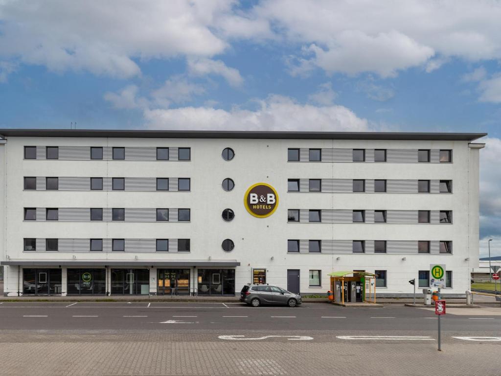 劳森豪森B&B HOTEL Frankfurt-Hahn Airport的前面有一辆汽车停放的白色建筑