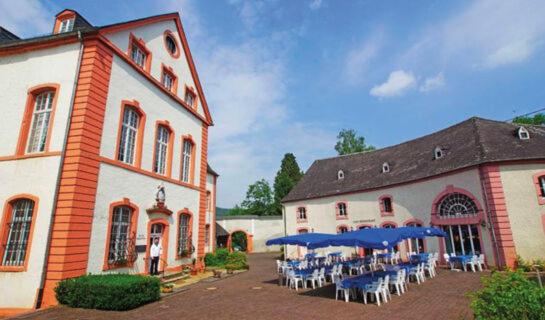 博伦多夫Burg Bollendorf by PRISMA的庭院内带桌子和蓝色遮阳伞的建筑
