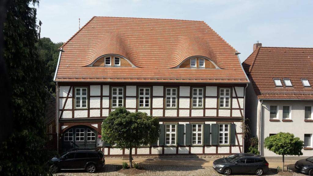 马尔洛Ferienwohnung "Im Pfarrhaus Marlow"的一座红色屋顶的房子和两辆停在前面的汽车