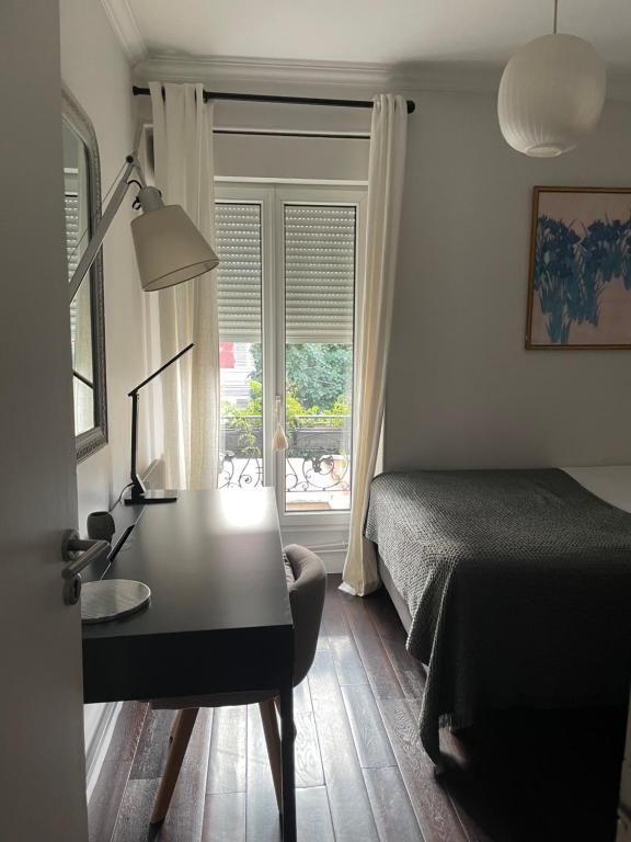 布洛涅-比扬古MAISON STANDING PROCHE ROLAND GARROS et JO 2024的一间卧室配有书桌、床和窗户。