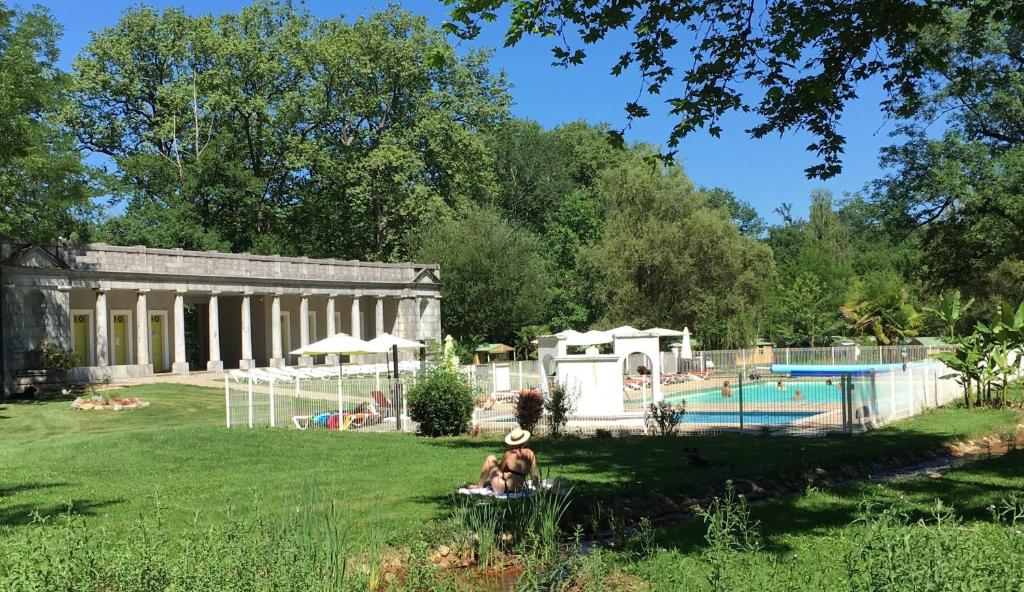 圣吉隆Camping Parc d'Audinac Les Bains的一群人坐在游泳池旁的草地上