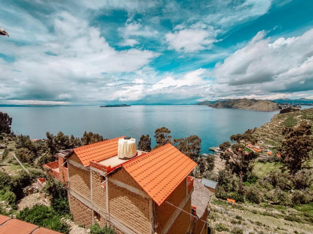 Comunidad YumaniHostal Isla del Sol的水边有橙色屋顶的房子