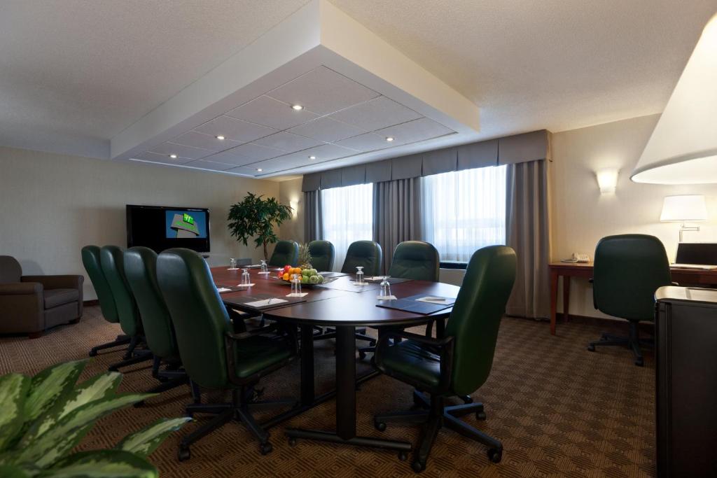 拉瓦尔拉瓦尔蒙特利尔假日酒店的一间会议室,配有桌子和绿色椅子
