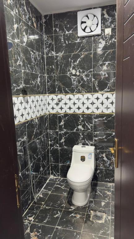 Al Bad‘فندق الاقامة السعيدة的黑色瓷砖浴室设有白色卫生间