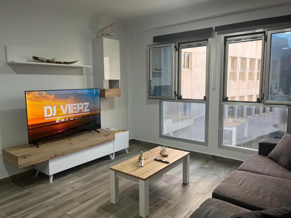 加尔达尔Acogedor apartamento con piscina yedae的客厅配有电视、沙发和桌子