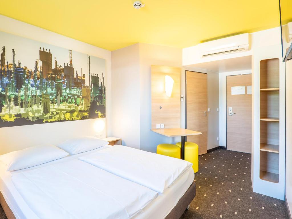 莱茵河畔路德维希港路德维希港B&B酒店的卧室配有白色的床和墙上的绘画作品
