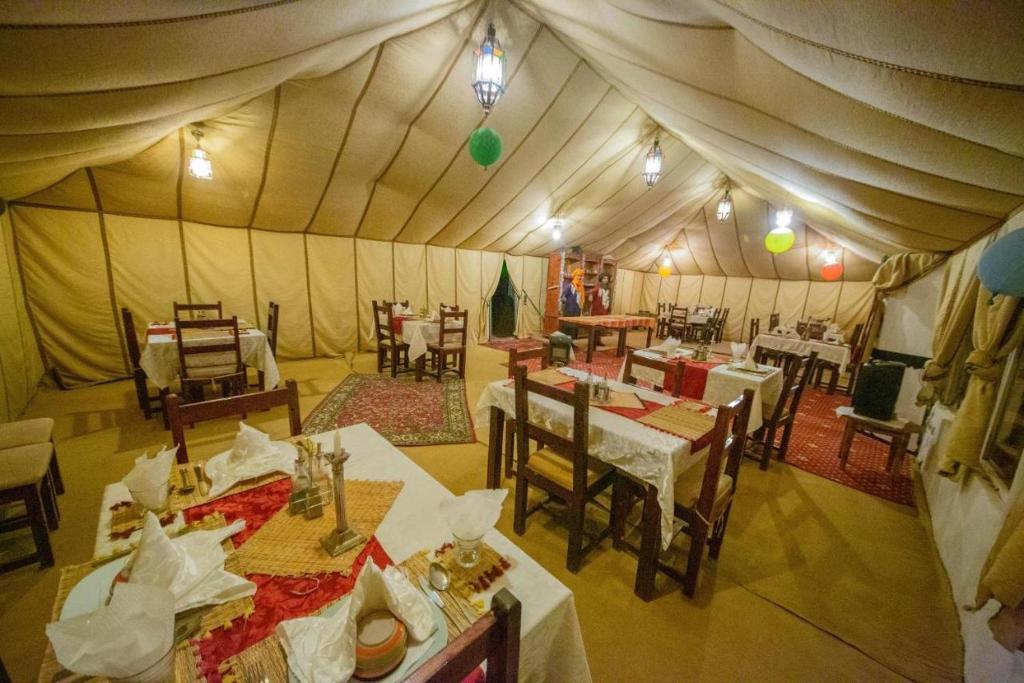 梅尔祖卡Desert Luxury Camp Experience的帐篷内带桌椅的用餐室