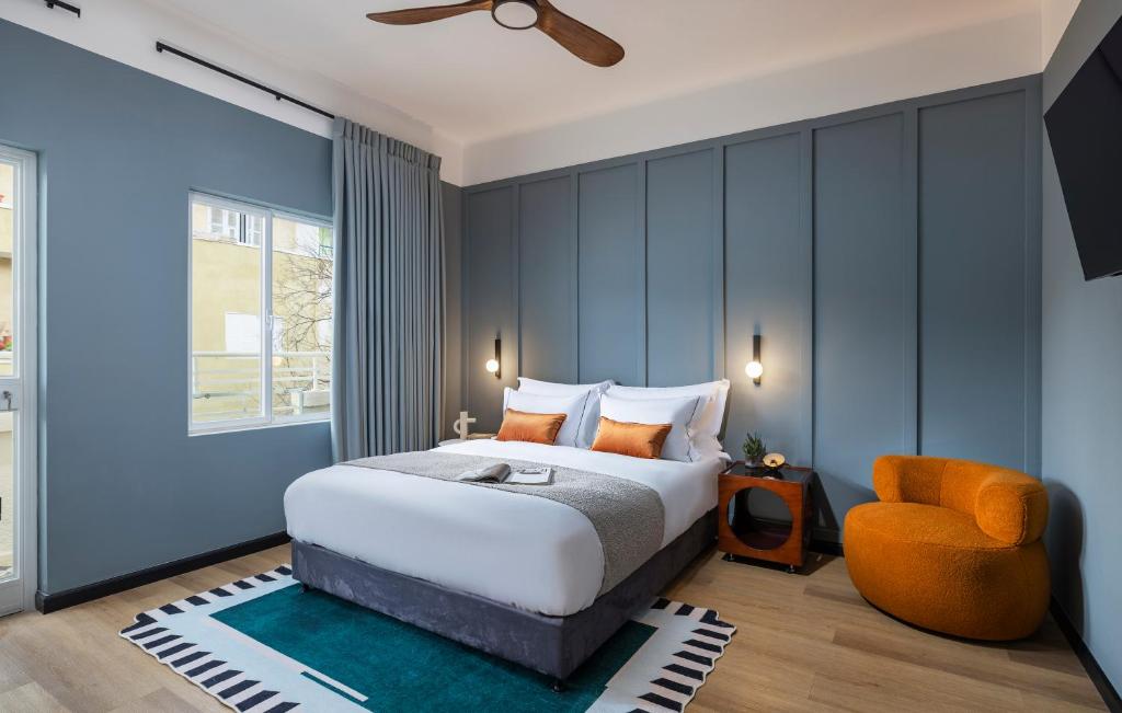 特拉维夫Albi Florentin的一间卧室配有一张床和一张橙色椅子