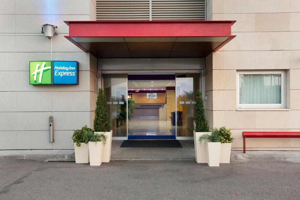 阿尔考空Holiday Inn Express Madrid-Alcorcón, an IHG Hotel的门和植物的建筑物入口