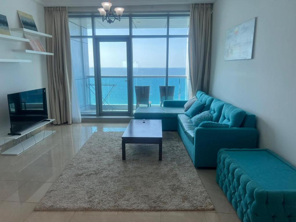 阿吉曼Sunset Beach View Holiday Homes的客厅配有蓝色的沙发和桌子