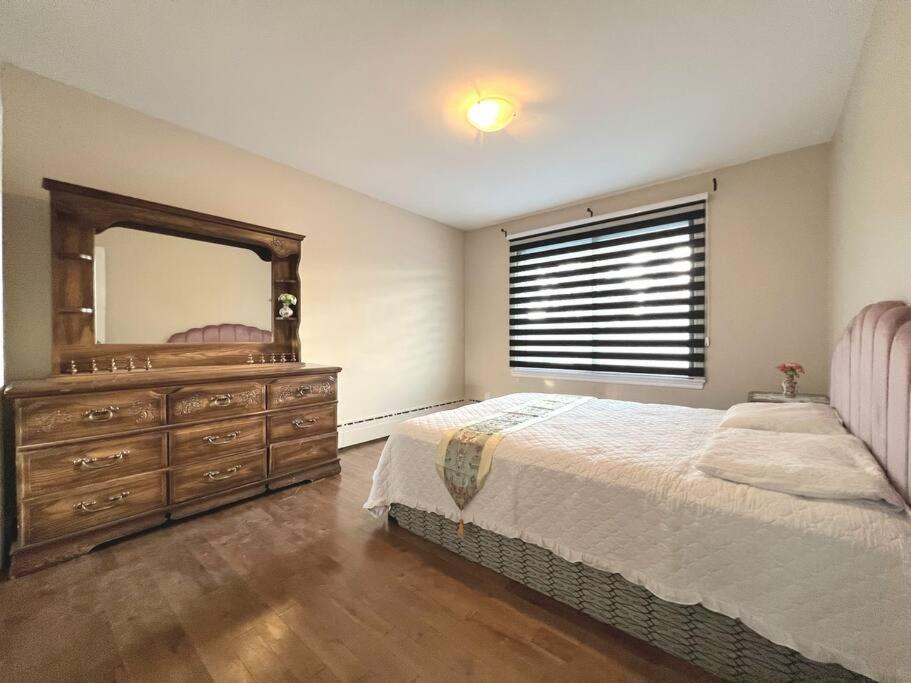 拉瓦尔Comfortable entire 3BDR Apt in Laval Montreal的一间卧室配有一张床和一个带镜子的梳妆台