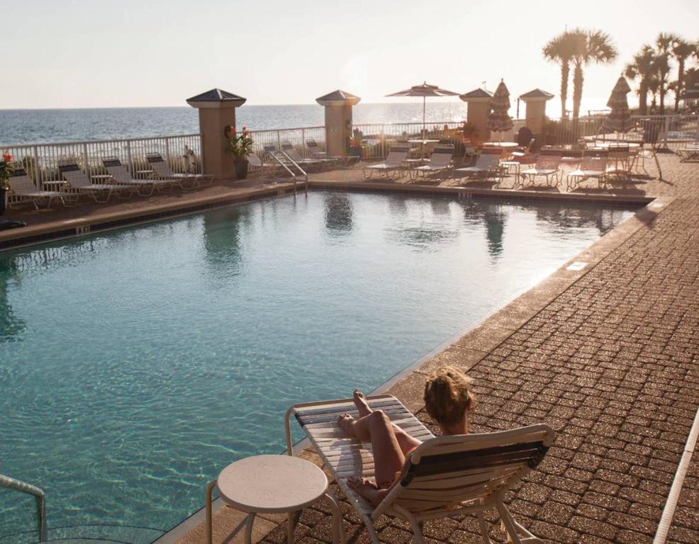 巴拿马城海滩Holiday Inn Club Vacations Panama City Beach Resort的坐在游泳池旁椅子上的女人