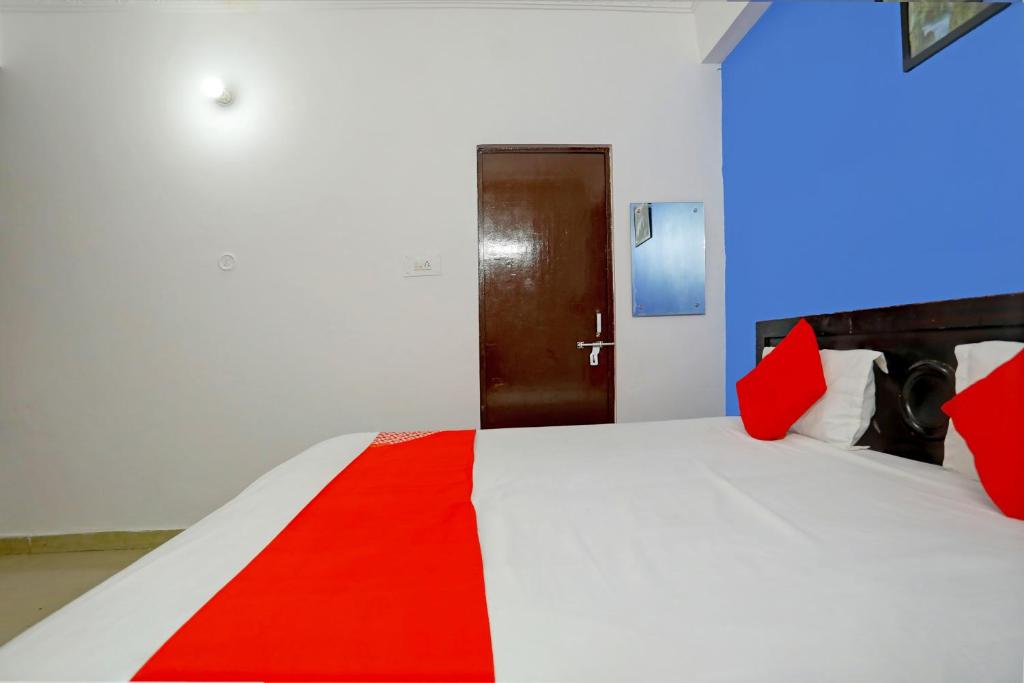 HasanganjOYO Flagship Hotel Drip Inn的一间卧室配有一张带红色枕头的床和一扇门