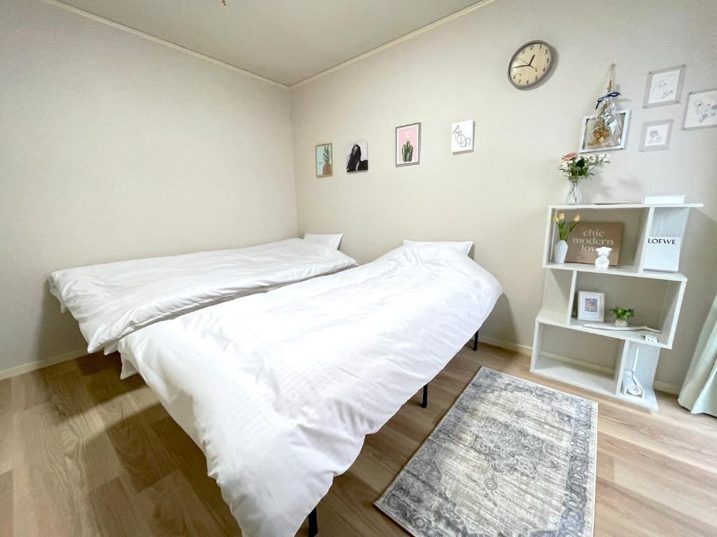 东京Gest Residence EDORIVER Airport Line Self check in的一间卧室配有一张带白色床单的床和时钟