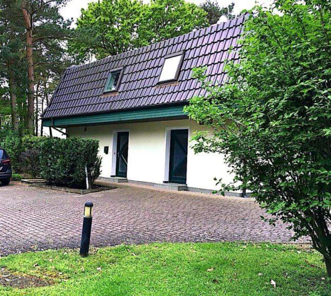 Kölpinsee auf UsedomFerienwohnung Achterhuus的砖车道上一座白色房子,屋顶黑色