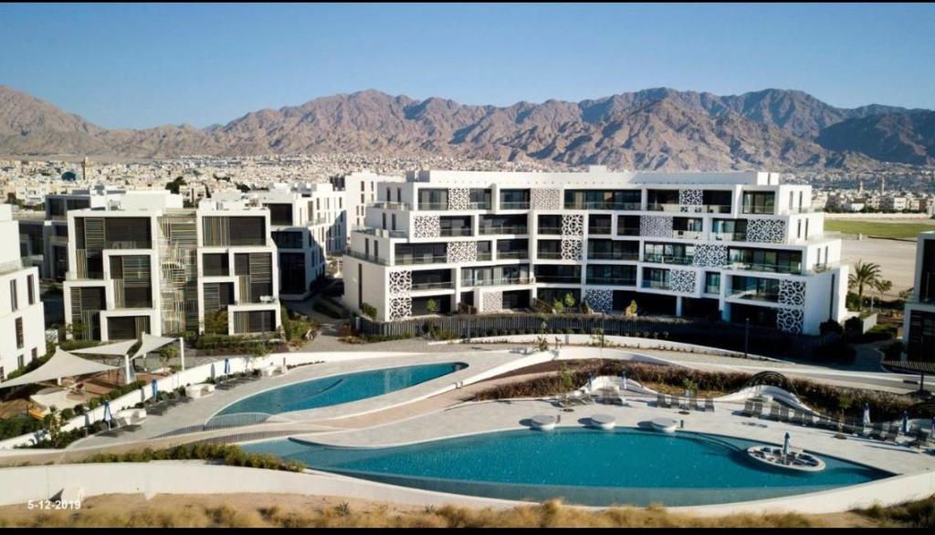 亚喀巴The Oasis Luxury Apartment的一座大型公寓楼,前面设有一个游泳池