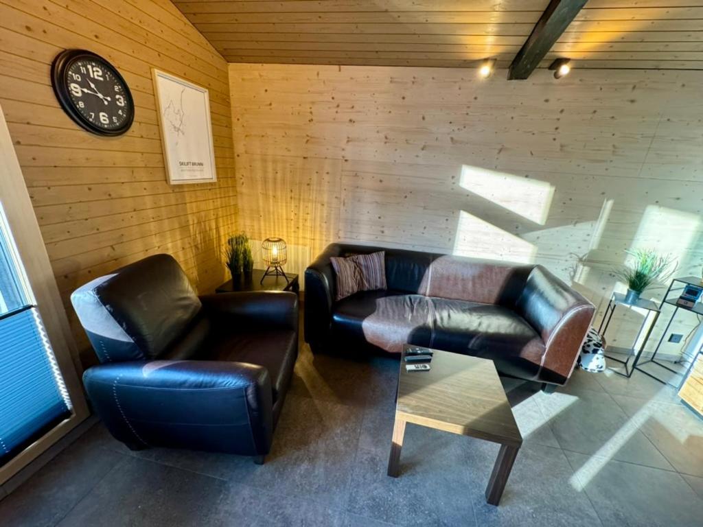 AlpthalFerienwohnung Brunni-Lodge direkt am Grossen Mythen的客厅配有两张真皮沙发和一个时钟
