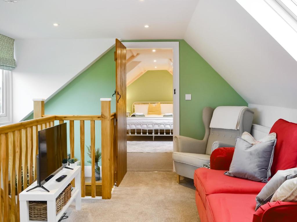 HaytonCartwheel Cottage的一间带红色沙发的客厅和楼梯