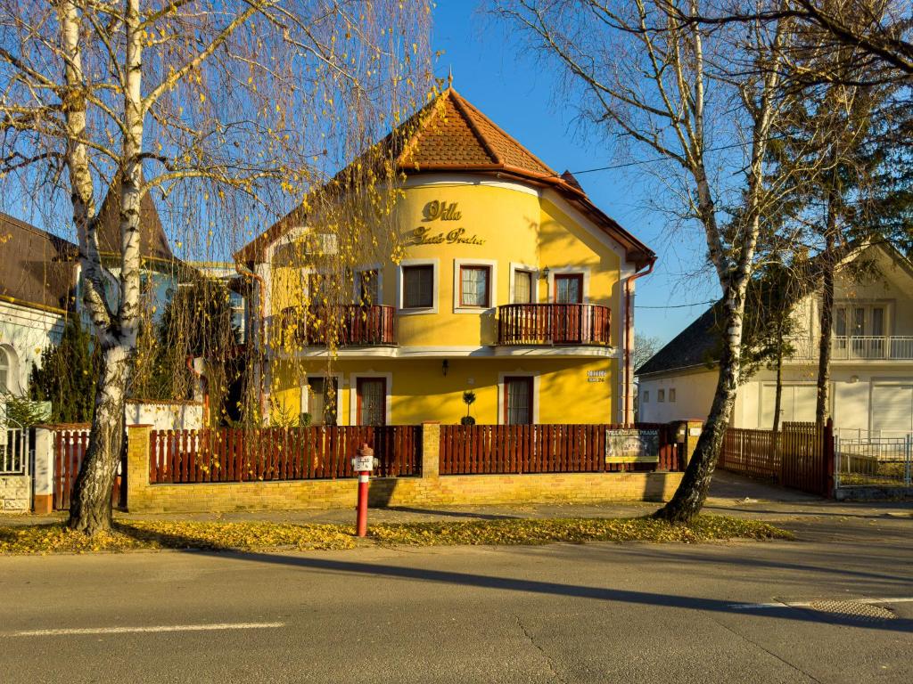 赫维兹泽拉塔普拉哈别墅酒店的黄色房子,有栅栏和消防栓