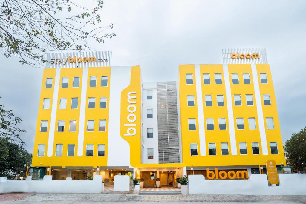 古尔冈Bloom Hotel - Medicity Gurugram, Near Medanta Hospital的两座黄色建筑,上面有吊椅标志