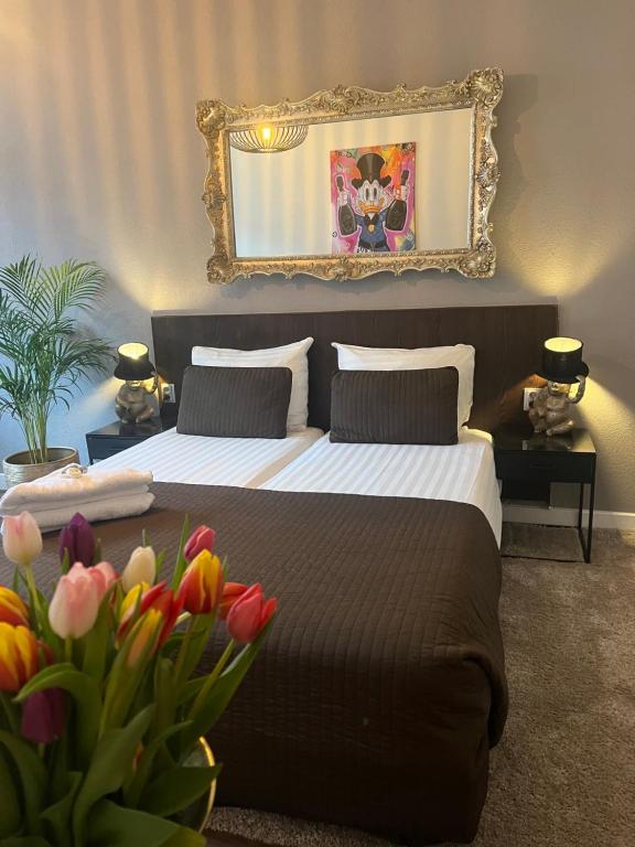 鹿特丹俄里翁酒店的一间卧室配有一张带镜子和鲜花的床