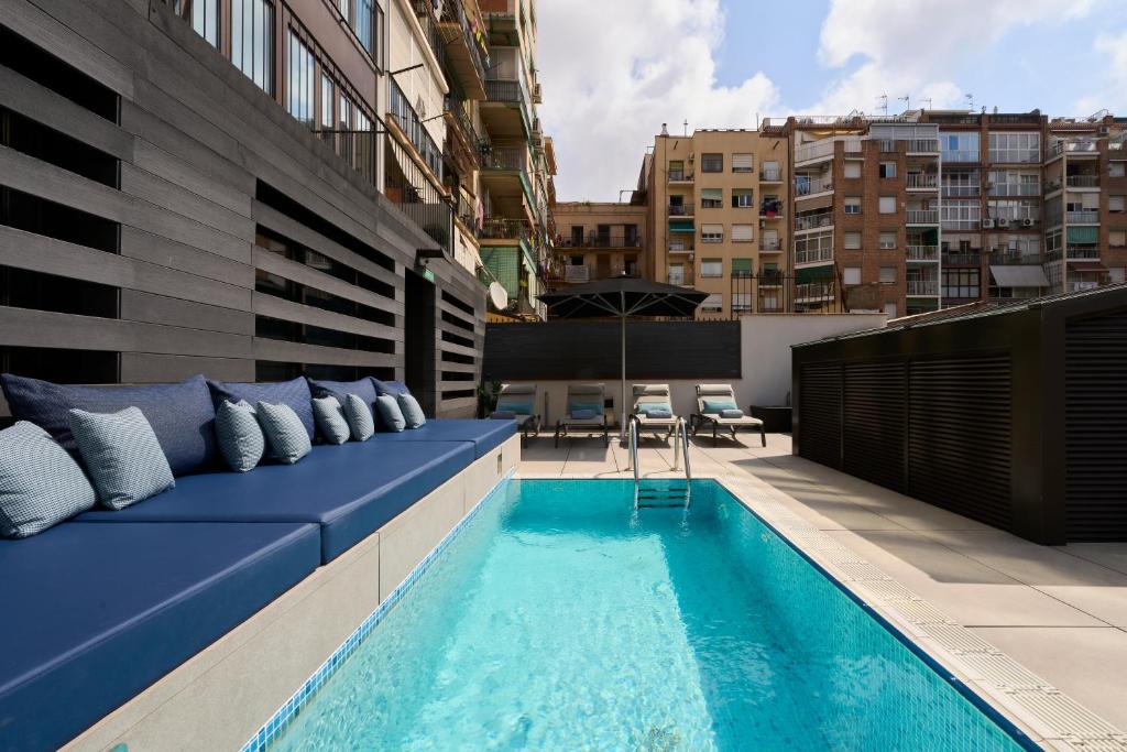 巴塞罗那巴塞罗那加泰罗尼亚格兰维亚大道酒店的一个带蓝色沙发的屋顶露台和一个游泳池