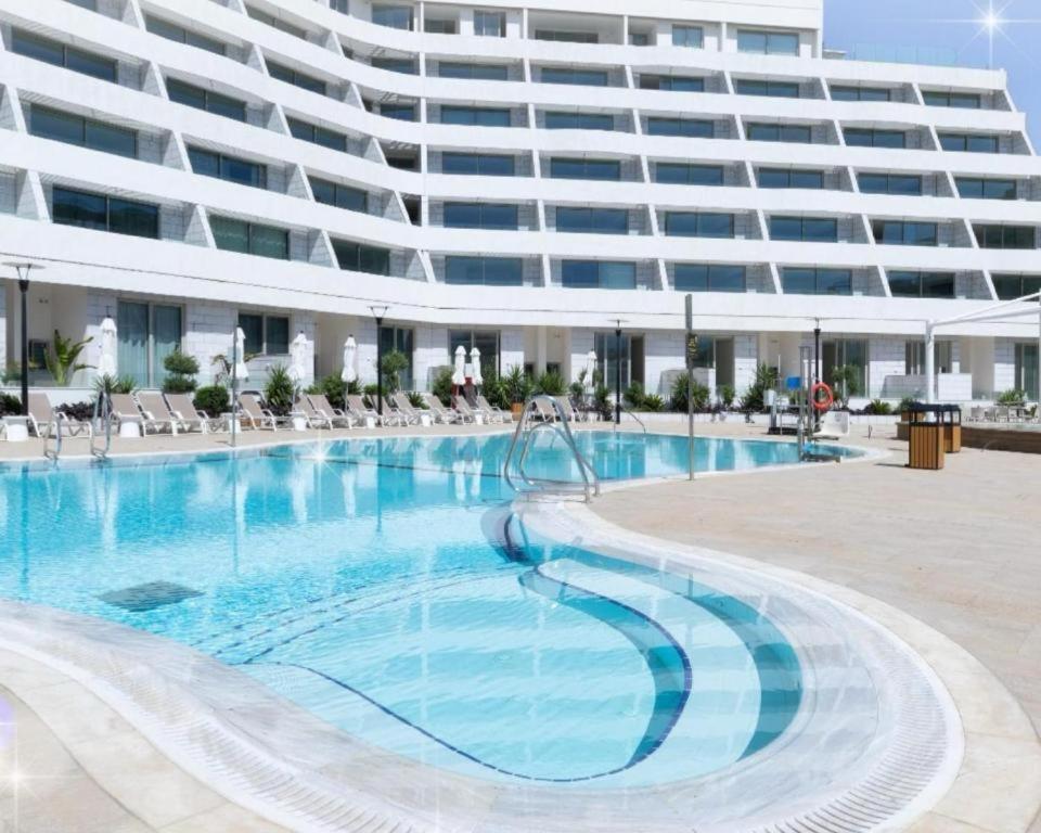 埃拉特Sansa suite SeaSide Sea View dream Apartment的大型公寓大楼,设有大型游泳池