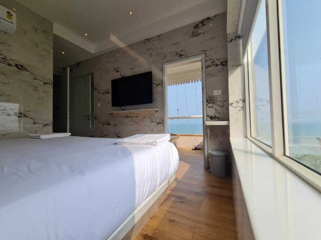 蓬蒂切里Lotus Rooms@Rockbeach的卧室配有白色的床和电视。