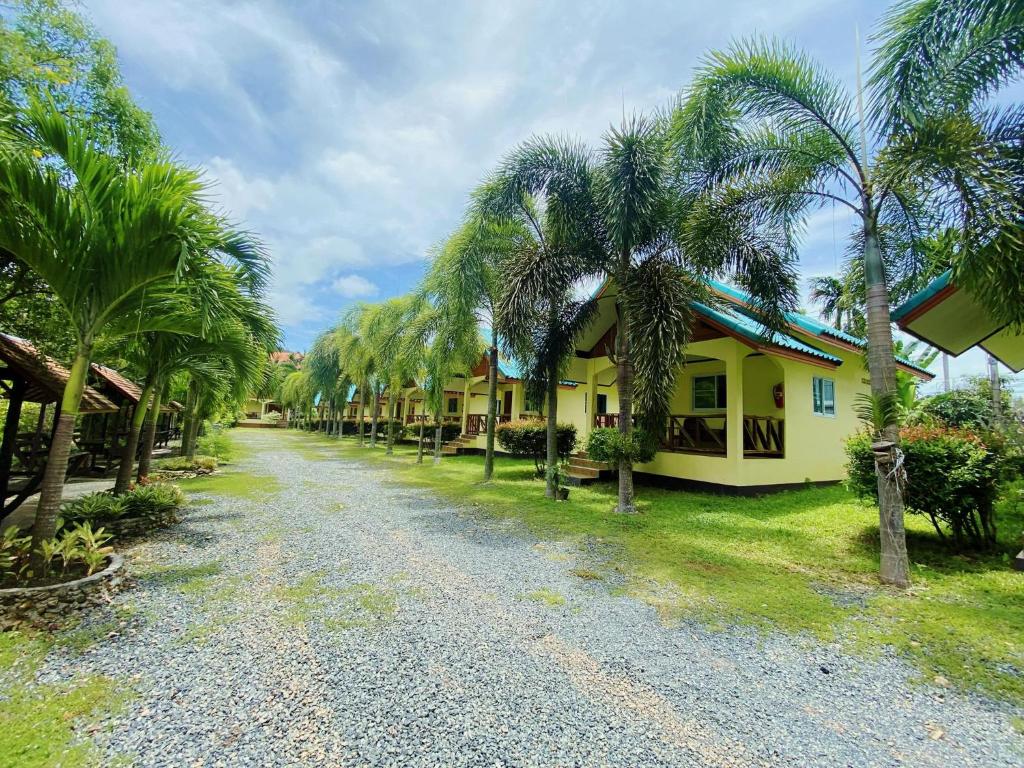 象岛Baanrimklong bungalow的一条在房子旁边连着棕榈树的道路