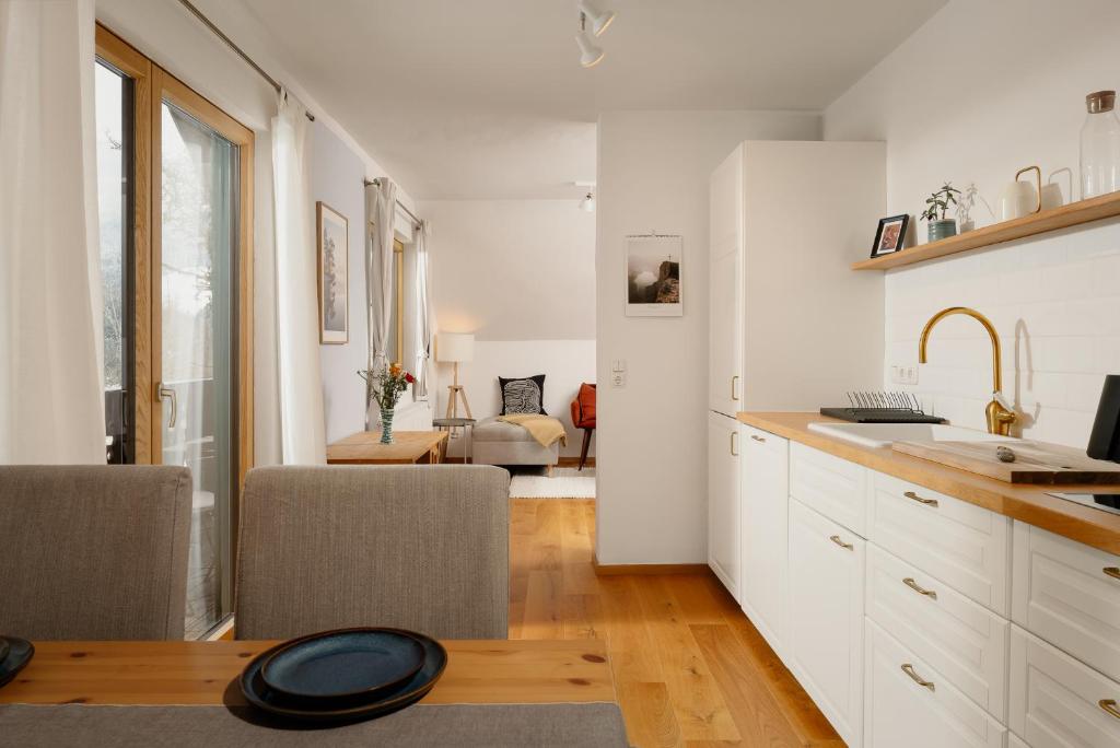 格伦德尔湖Haus Grundlsee的一间带白色橱柜的厨房和一间客厅