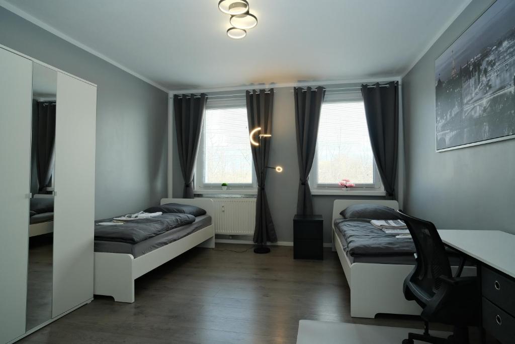 莱比锡Fit&Chill Apartment Sport, Entspannung & Netflix的客房设有两张床、一张书桌和两个窗户。