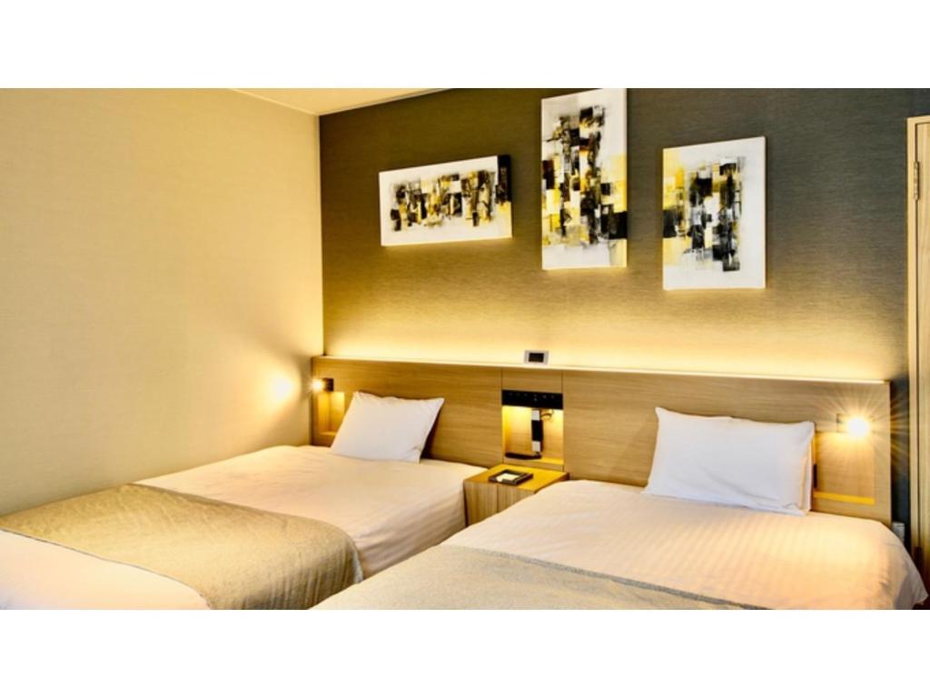 俱知安町Hotel Three M - Vacation STAY 93392v的两张位于酒店客房的床,墙上挂有照片