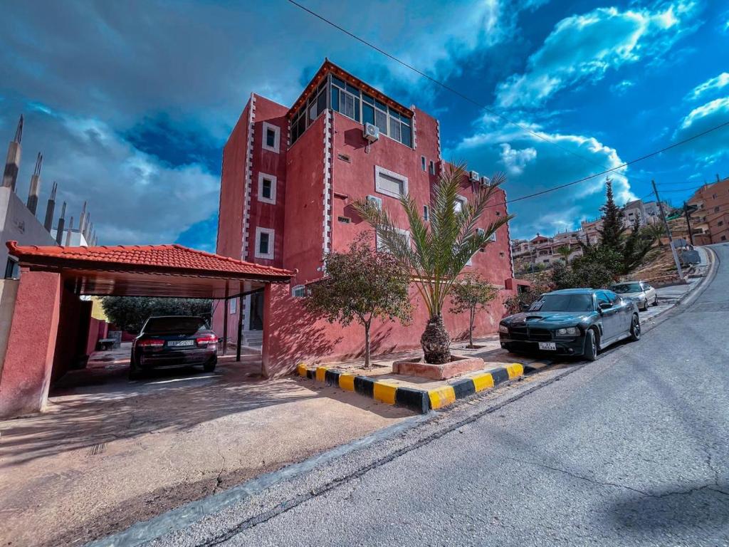 瓦迪穆萨Petra Caravan Guest House的一条在红楼前停有车辆的街道