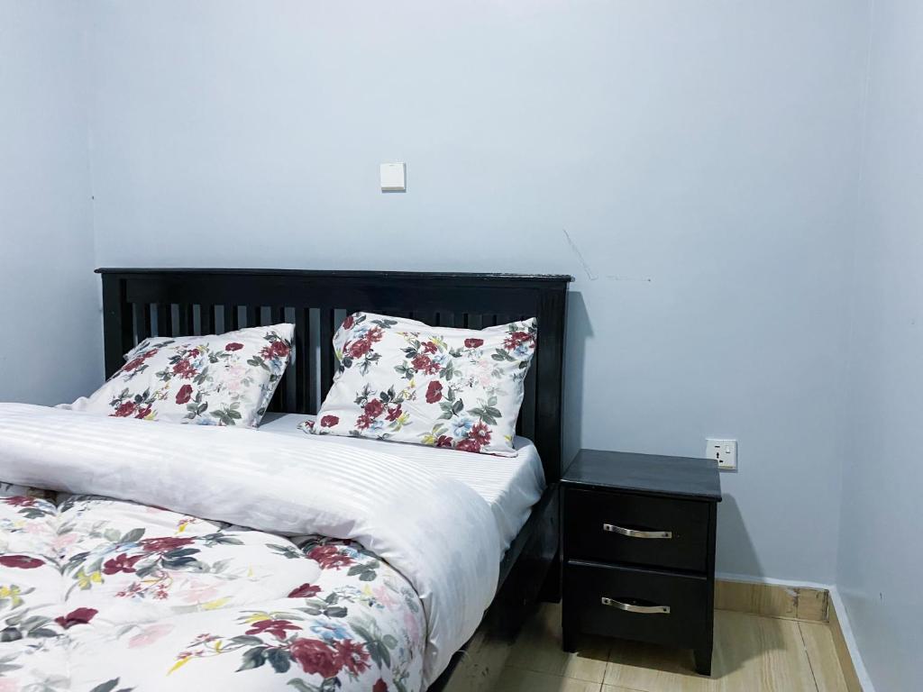 KigombeGahinga Sawa B&B的一间卧室配有一张带花卉枕头的床和床头柜