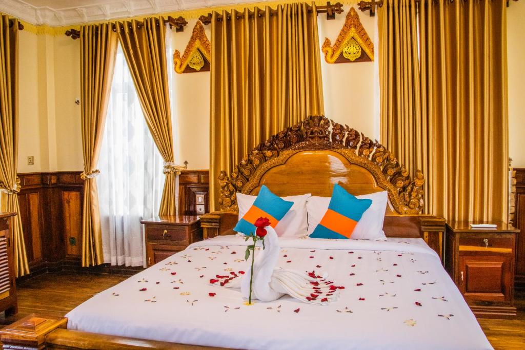 Phumĭ Puŏk ChăsPuok Hotel的一间卧室配有一张带鲜花的大床