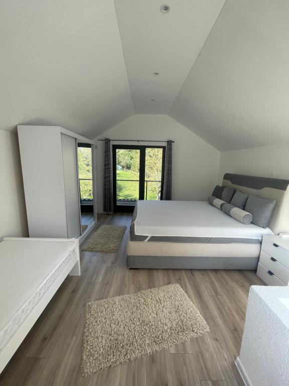 ZolaćiVikendica u prirodi na ranču的卧室配有一张白色的大床,铺有木地板