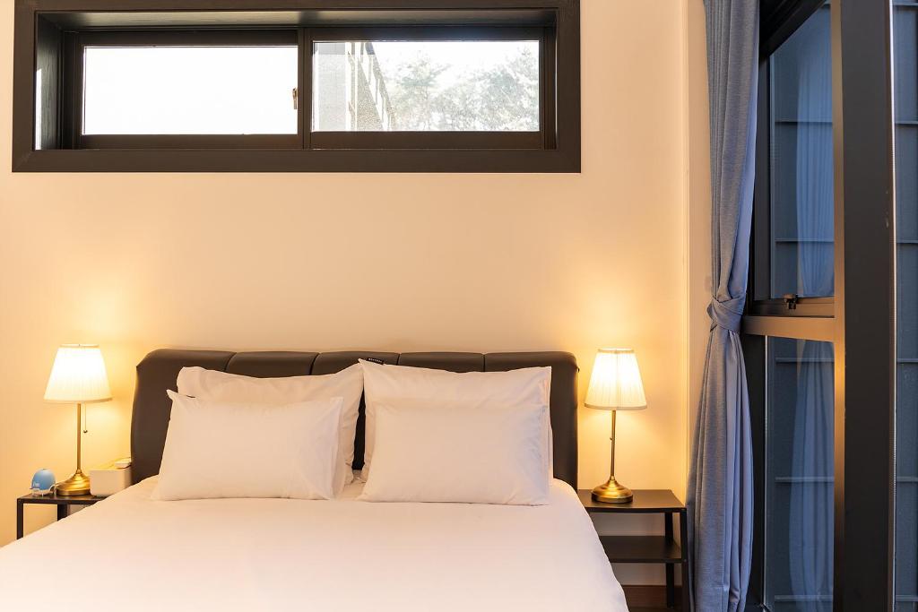 蔚山Private Pool Villa with filled with stars的卧室配有带白色枕头的床和窗户。