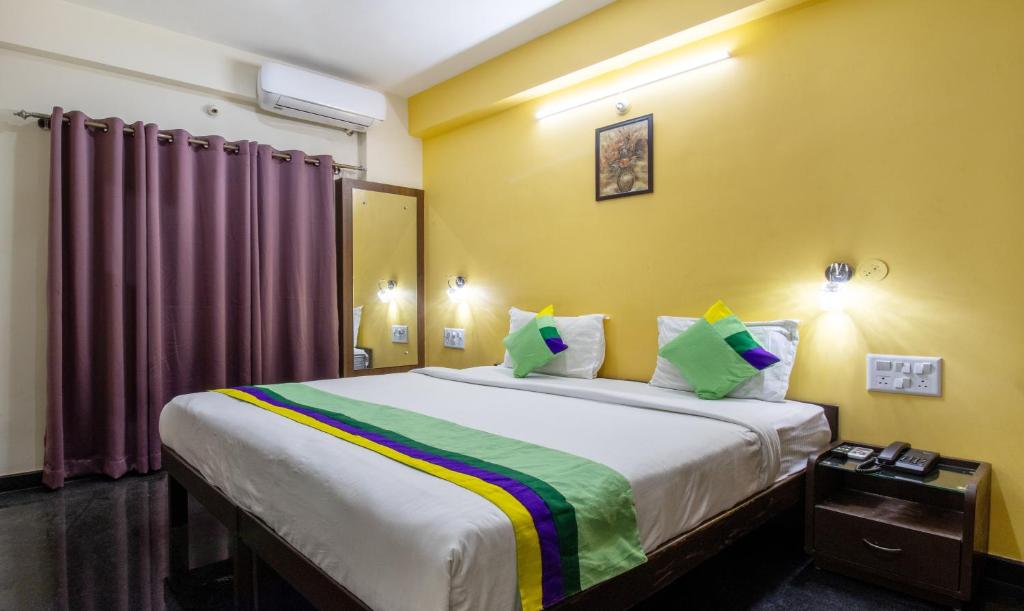 班加罗尔Treebo Trend RR Residency - Sanjay Nagar的一间卧室设有一张黄色墙壁的大床