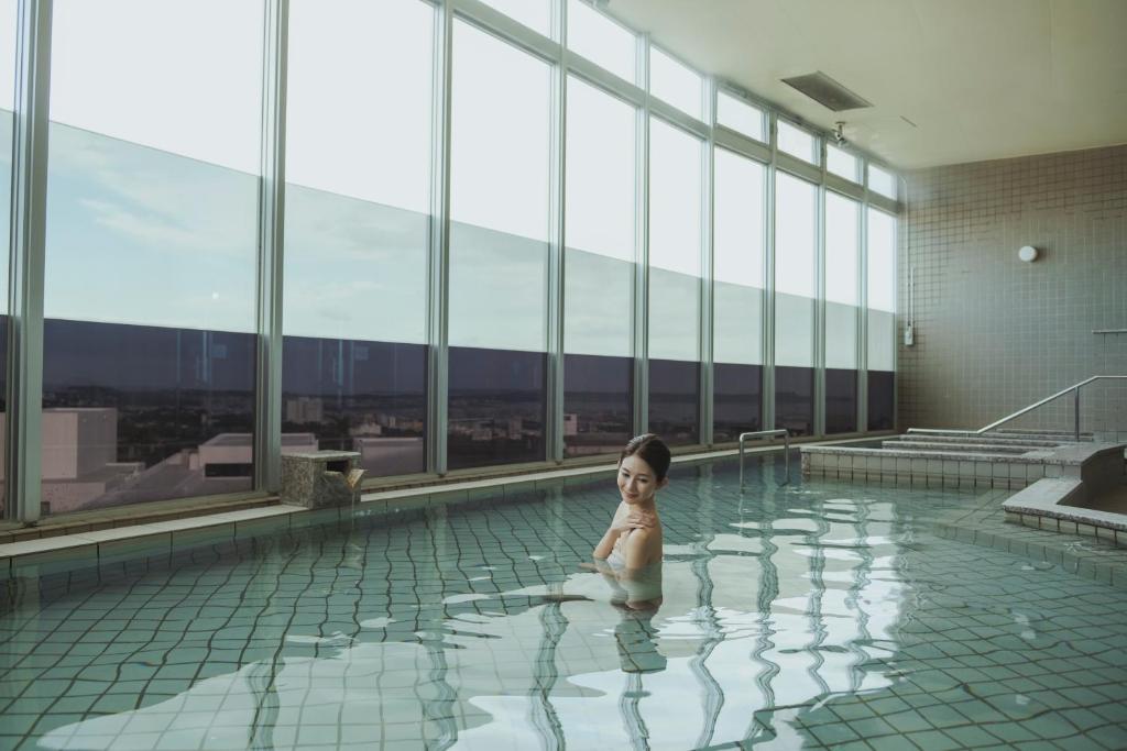 北中城村EM Wellness Kurashinohakko Lifestyle Resort的有一个小孩坐在游泳池里