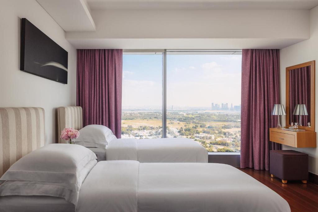 迪拜Jumeirah Living World Trade Centre Dubai的配有大窗户的酒店客房内的两张床